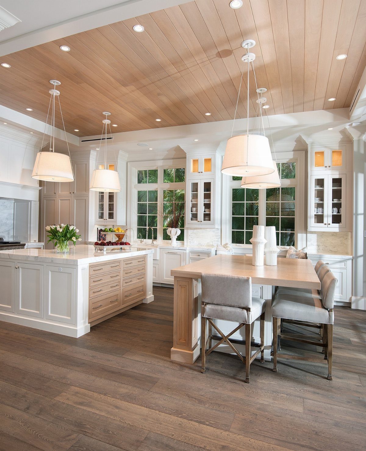 Two kitchen islands, one white and one wood, in a bright modern kitchen.