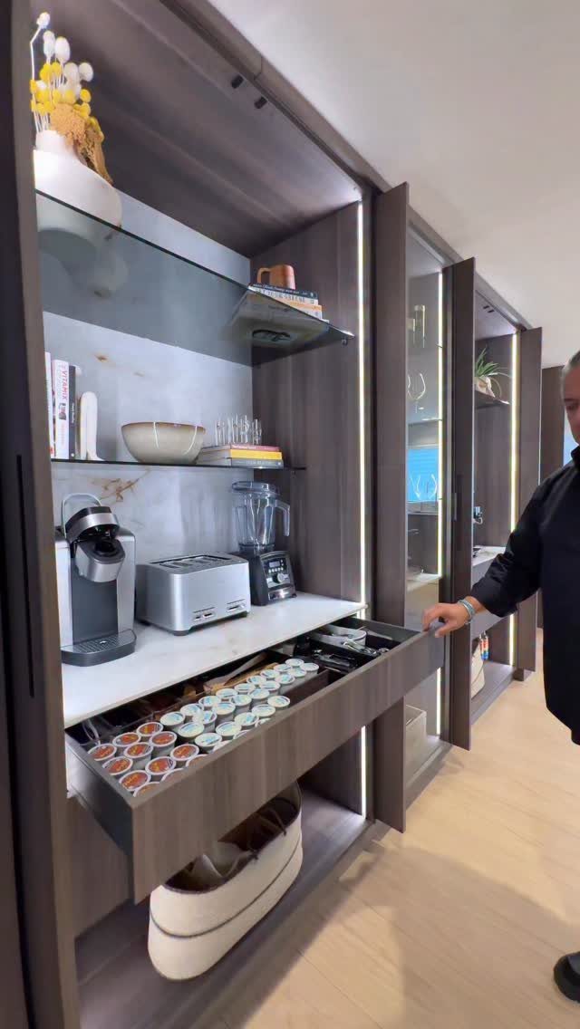 Modern dark wood coffee station with integrated lighting and a pull-out pod drawer.