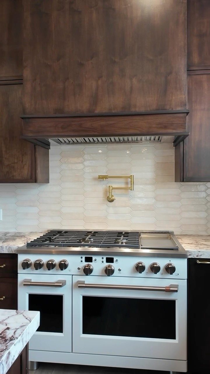 Large dark wood range hood above a professional stainless steel stove and oven.