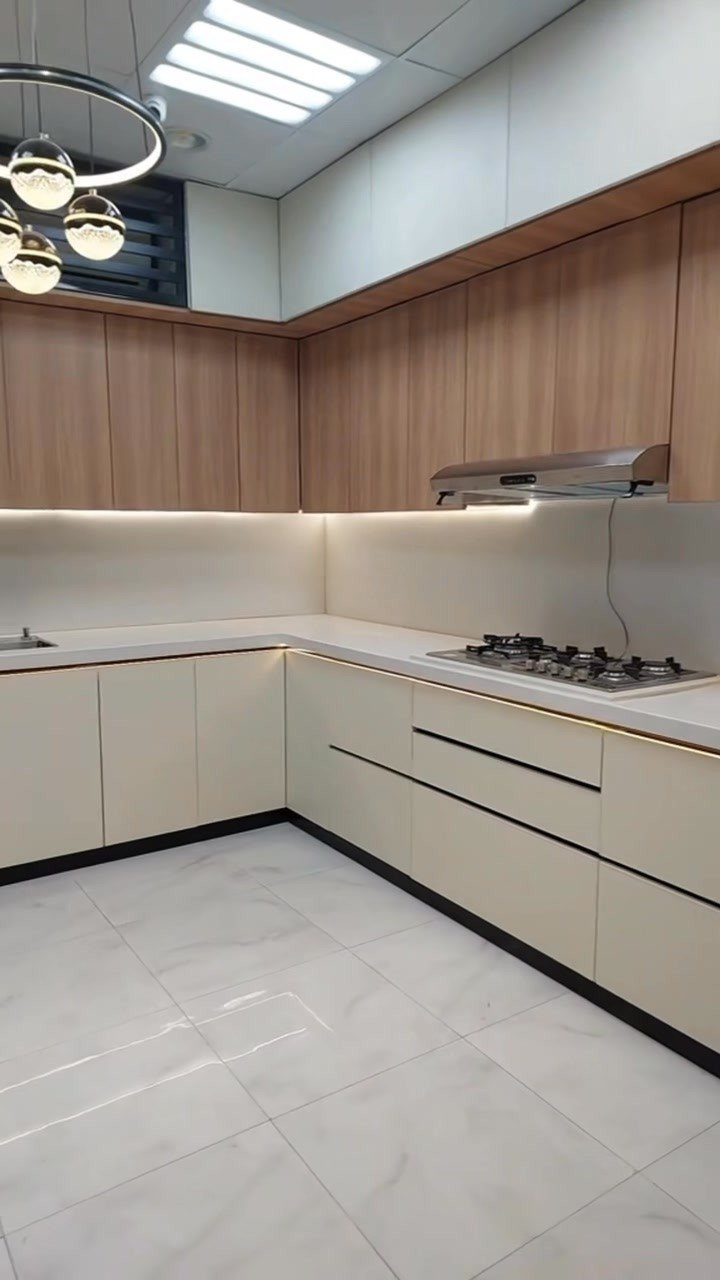 Modern kitchen with light wood upper cabinets and cream lower cabinetry and white countertops.