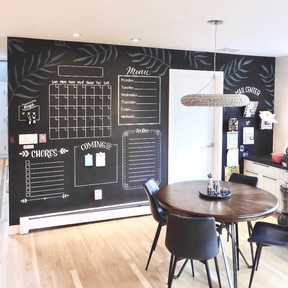 Black chalkboard accent wall with hand-drawn menus and calendars in a dining room