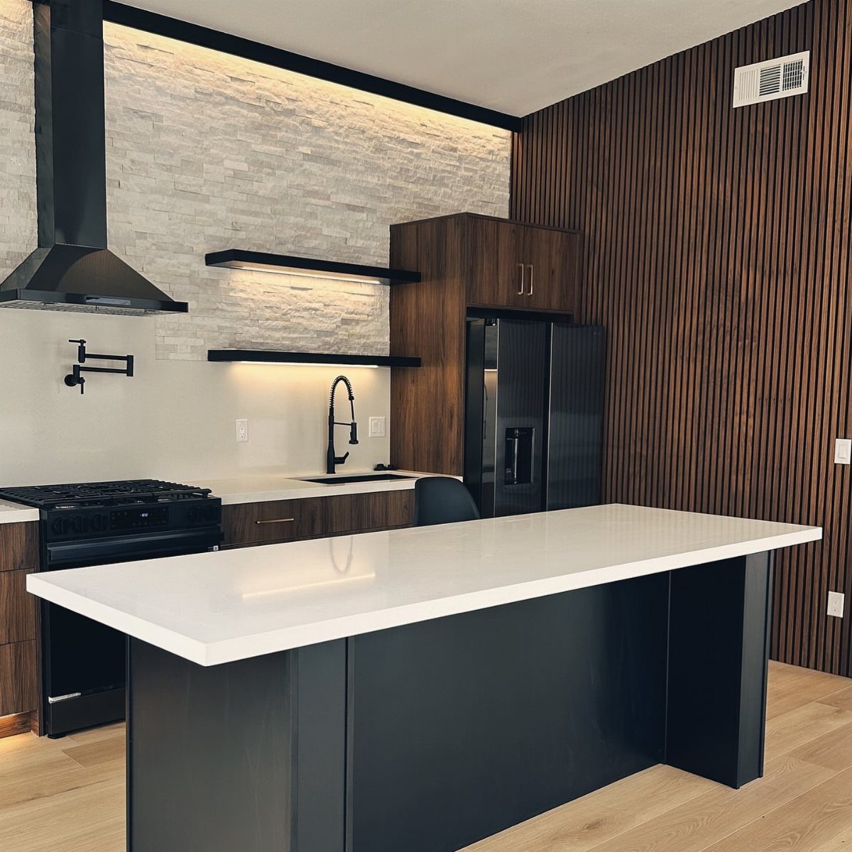 Modern kitchen with a white stone textured accent wall and wood slatted wall.