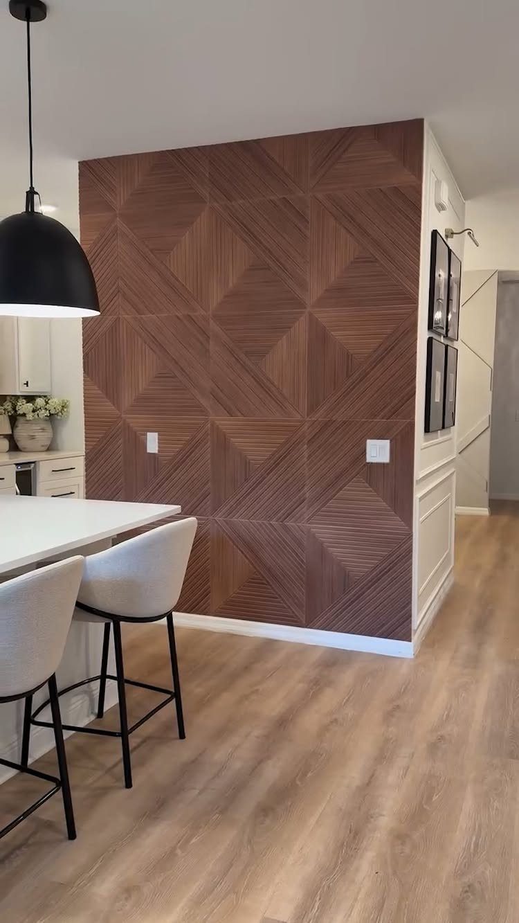 Brown geometric wood-paneled accent wall in a modern kitchen with white barstools.