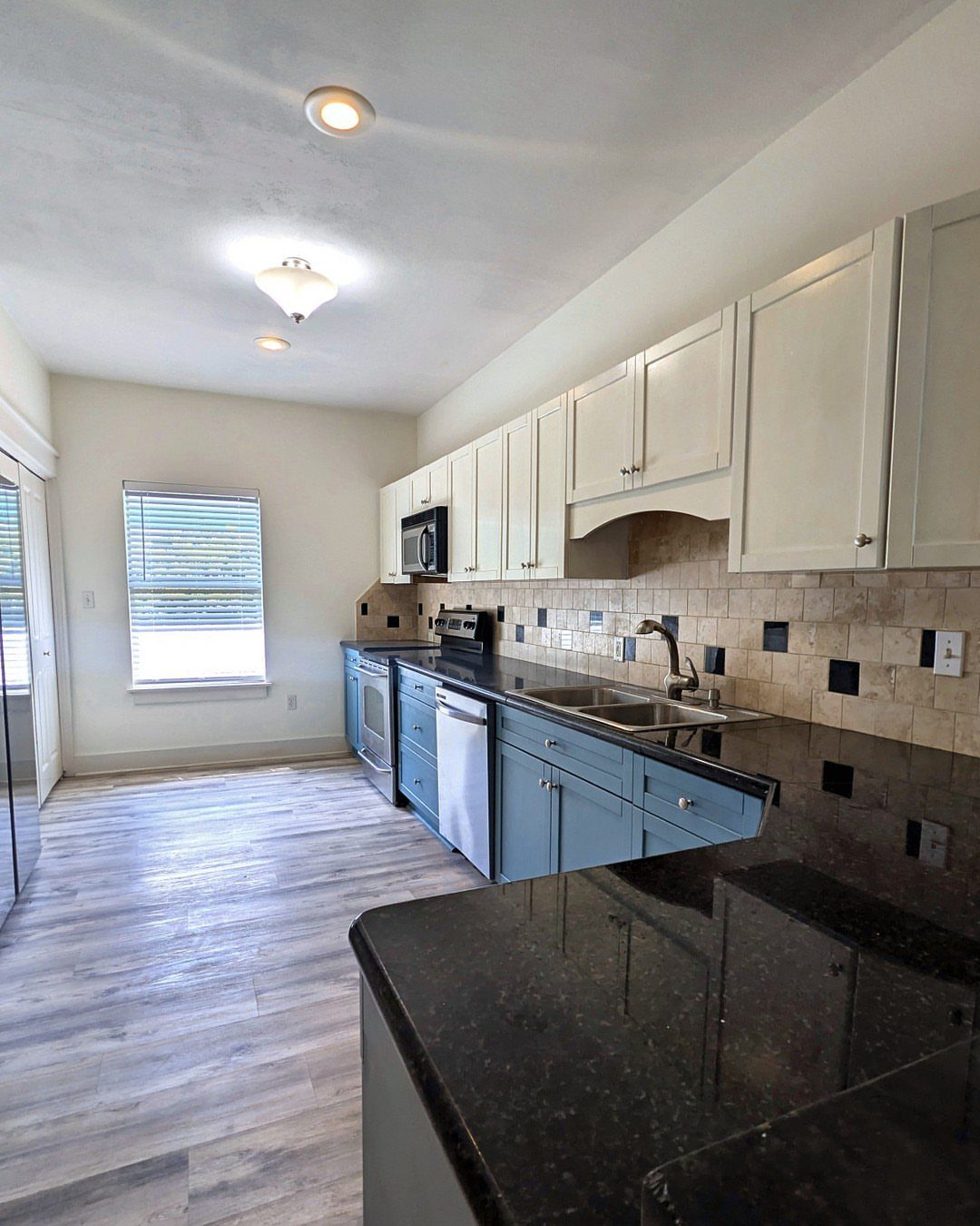 Blue lower cabinets and white upper cabinets with a beige tile backsplash.