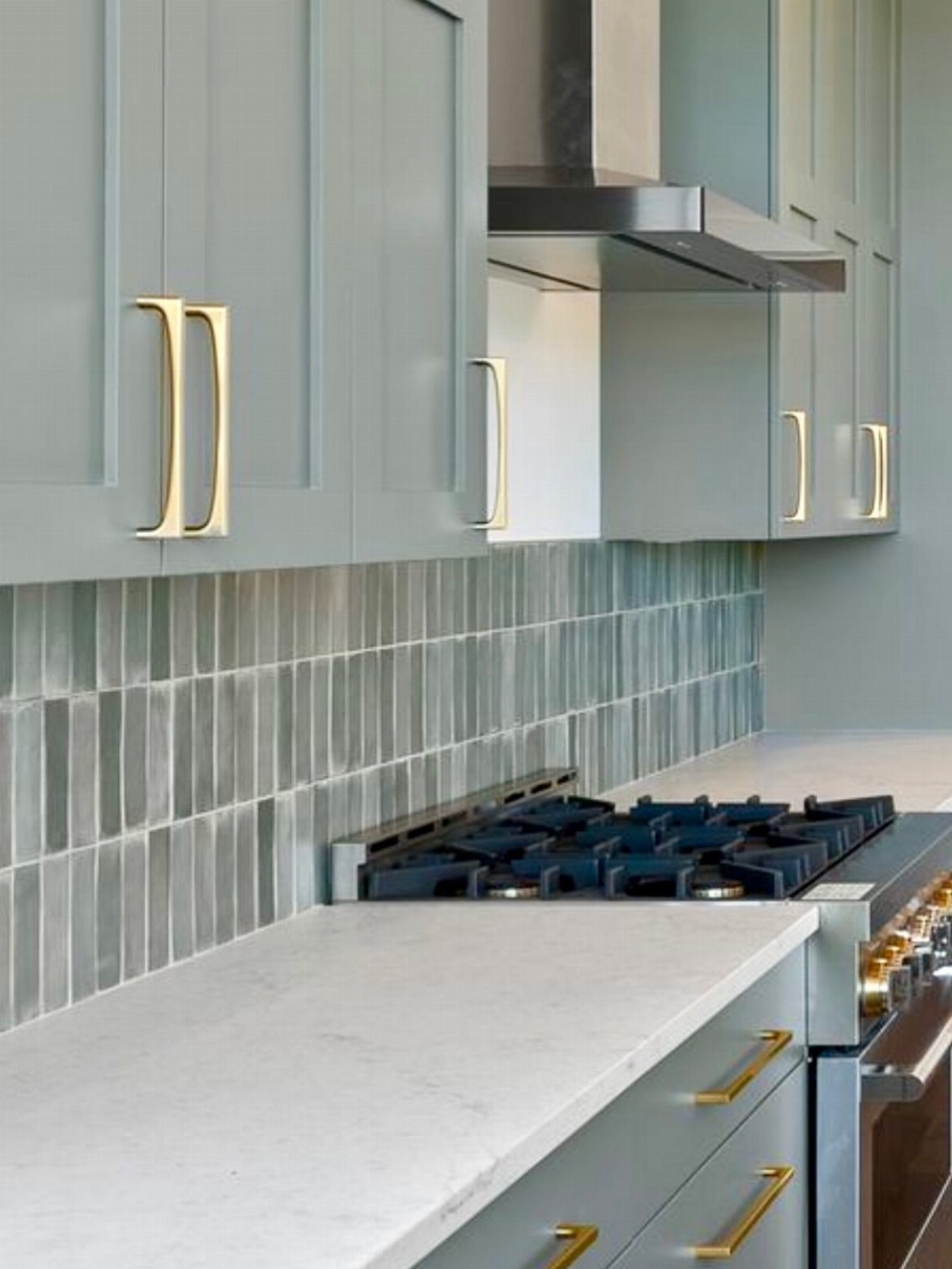 Pastel blue vertical tile backsplash between light blue cabinets and white marble countertops.