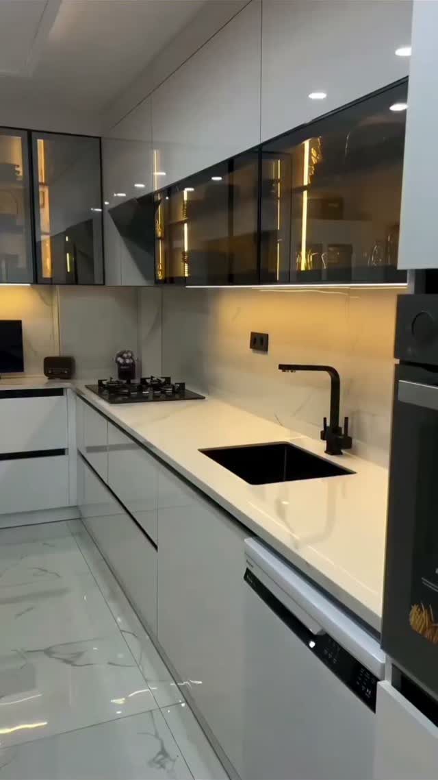 Modern kitchen with white cabinets, black glass uppers, and under-cabinet lighting.