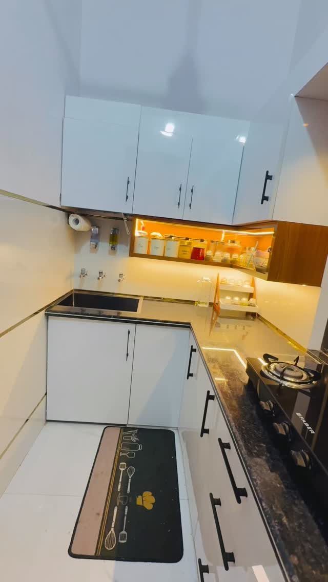 White kitchen cabinets with black handles and dark granite countertops in a modern kitchen.