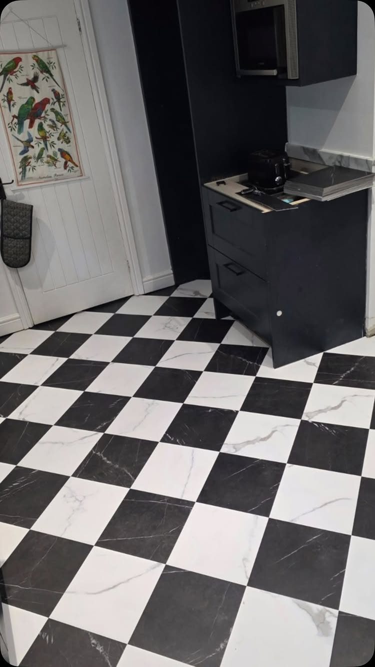 Black and white checkered marble floor in a kitchen with dark grey cabinets.