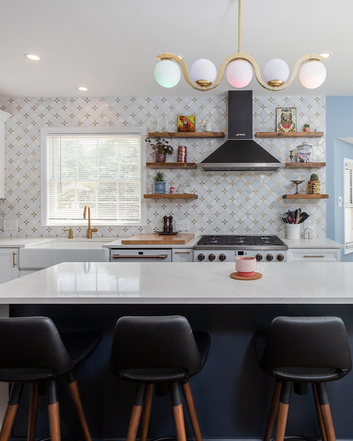 Kitchen with a black and white patterned tile backsplash and gold globe lighting.