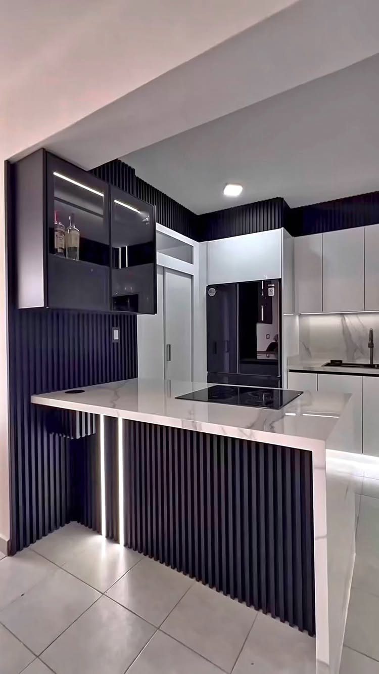 Modern kitchen with black fluted island, white marble countertops, and contrasting black and white cabinets.