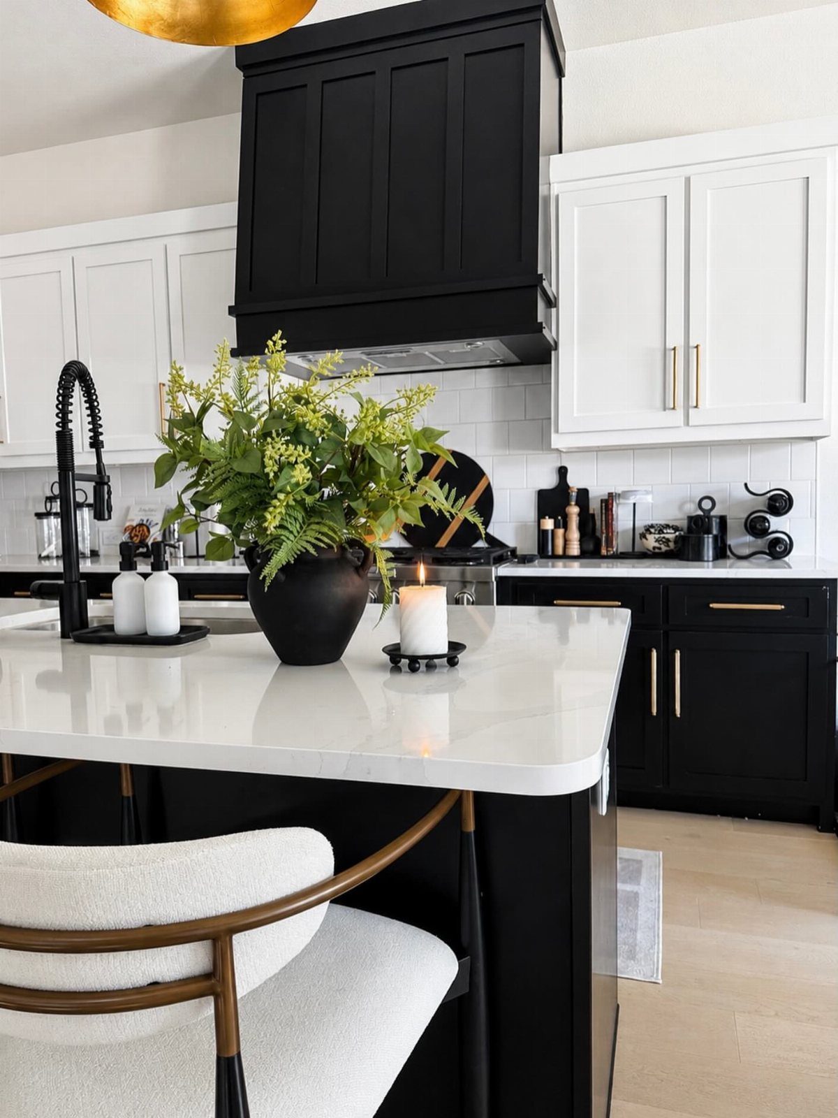 Modern kitchen with black and white cabinets featuring elegant gold hardware and marble countertops.