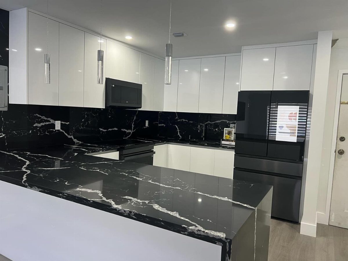 Modern kitchen with glossy white cabinets and black marble countertops with white veining.