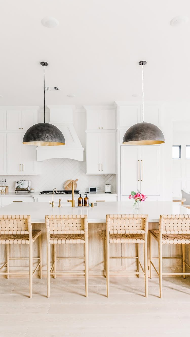 White kitchen with a large island and two black dome pendant lights hanging above.