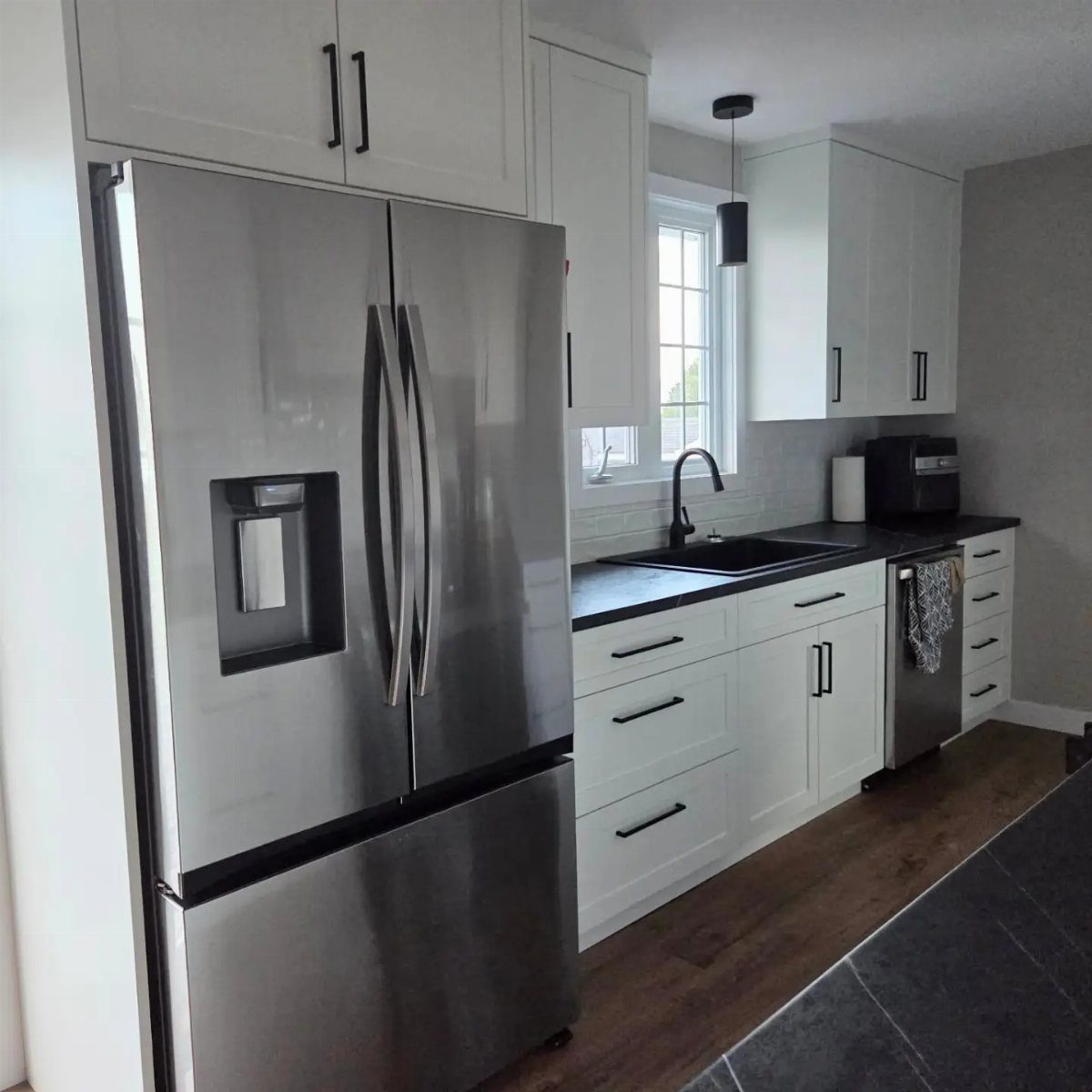 White shaker cabinets with black hardware and black countertops in a modern kitchen.