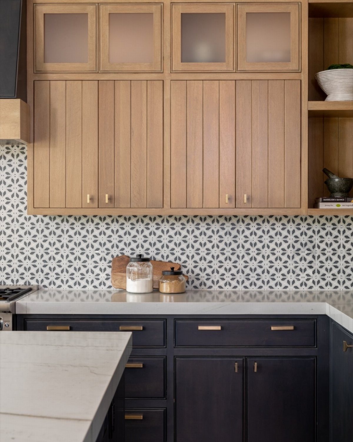 Black and white patterned tile backsplash between light wood and dark navy cabinets.