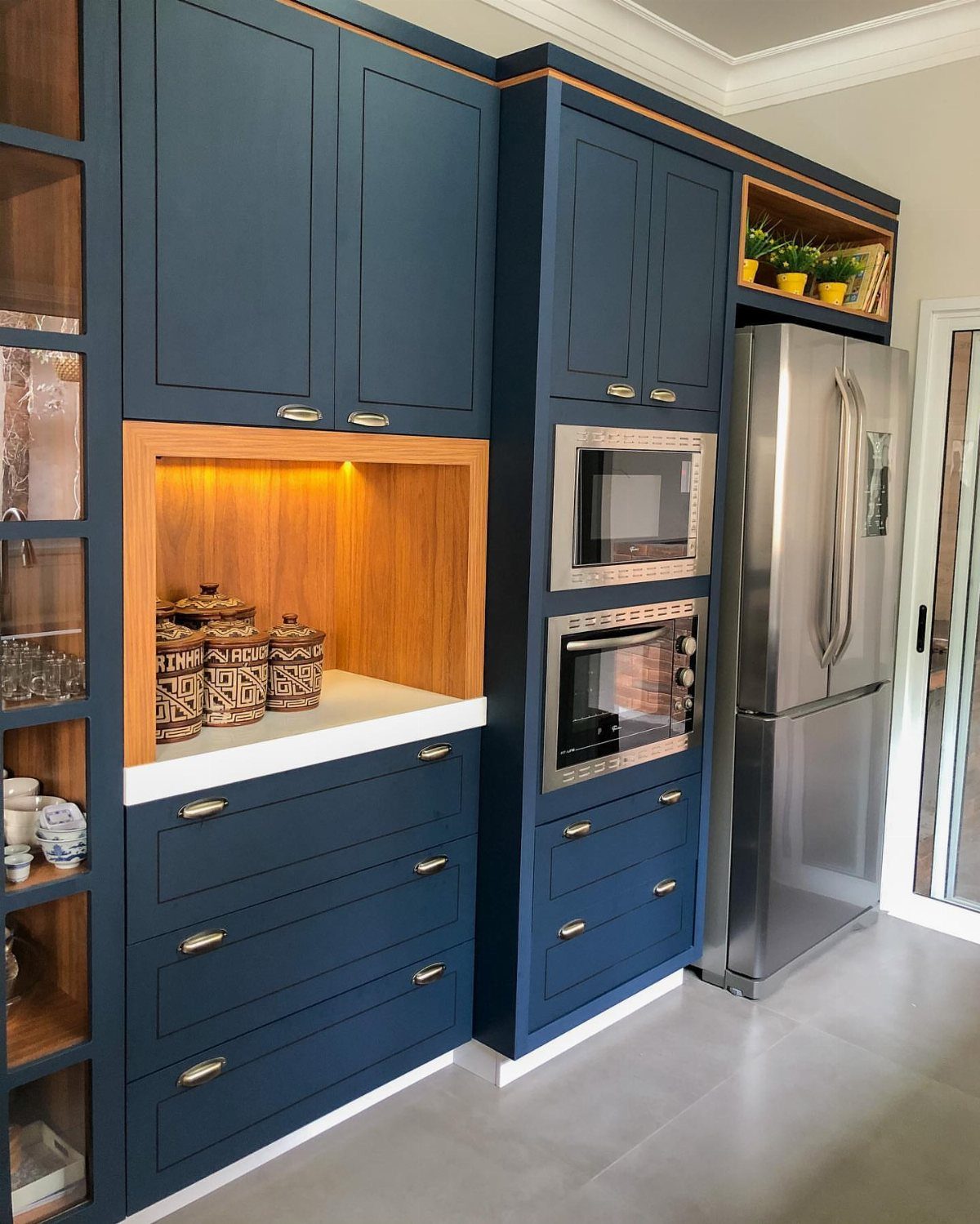 Dark blue kitchen cabinets featuring a warm wood-lined alcove and stainless steel appliances.