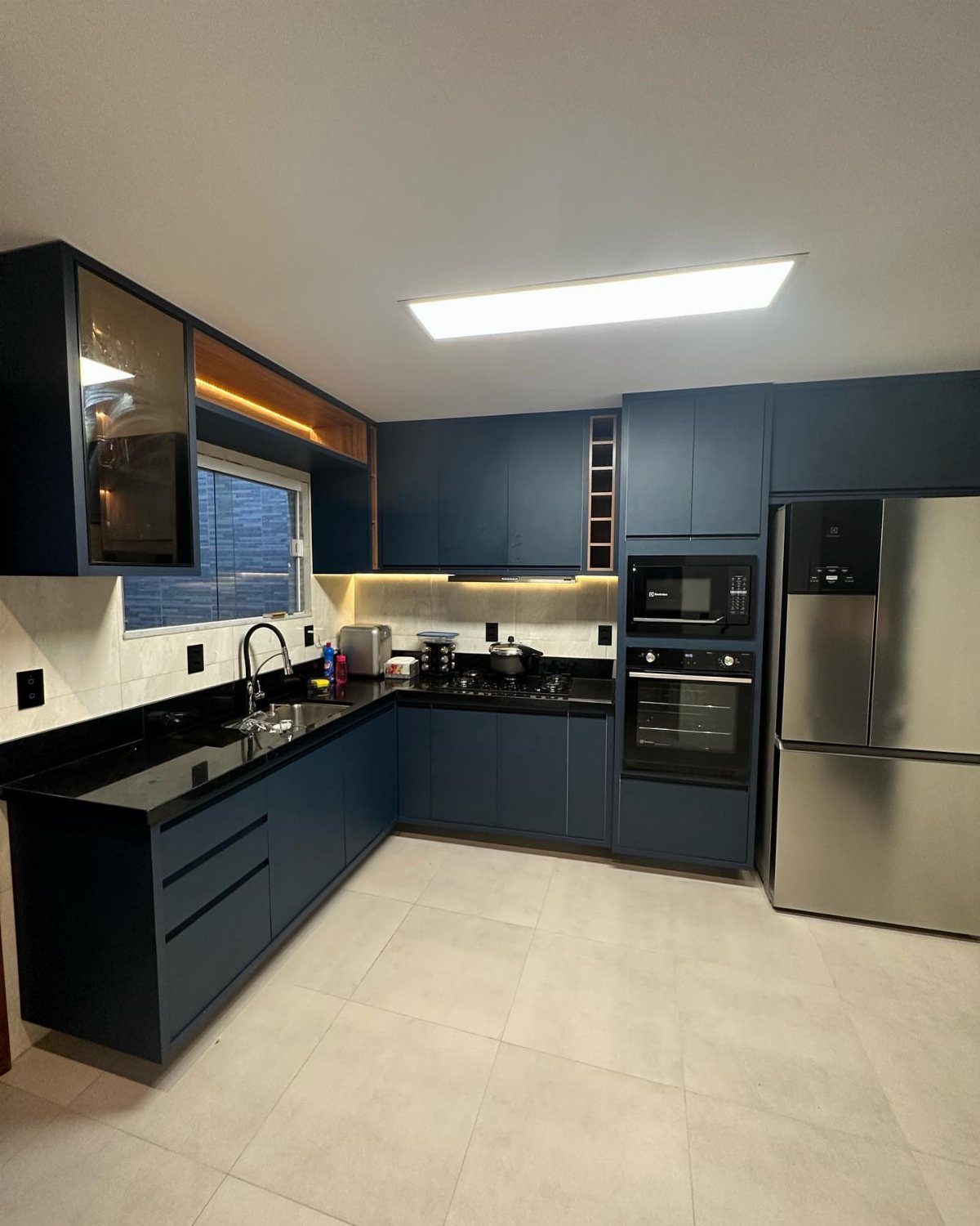 Deep blue kitchen cabinets with black countertops and stainless steel appliances.