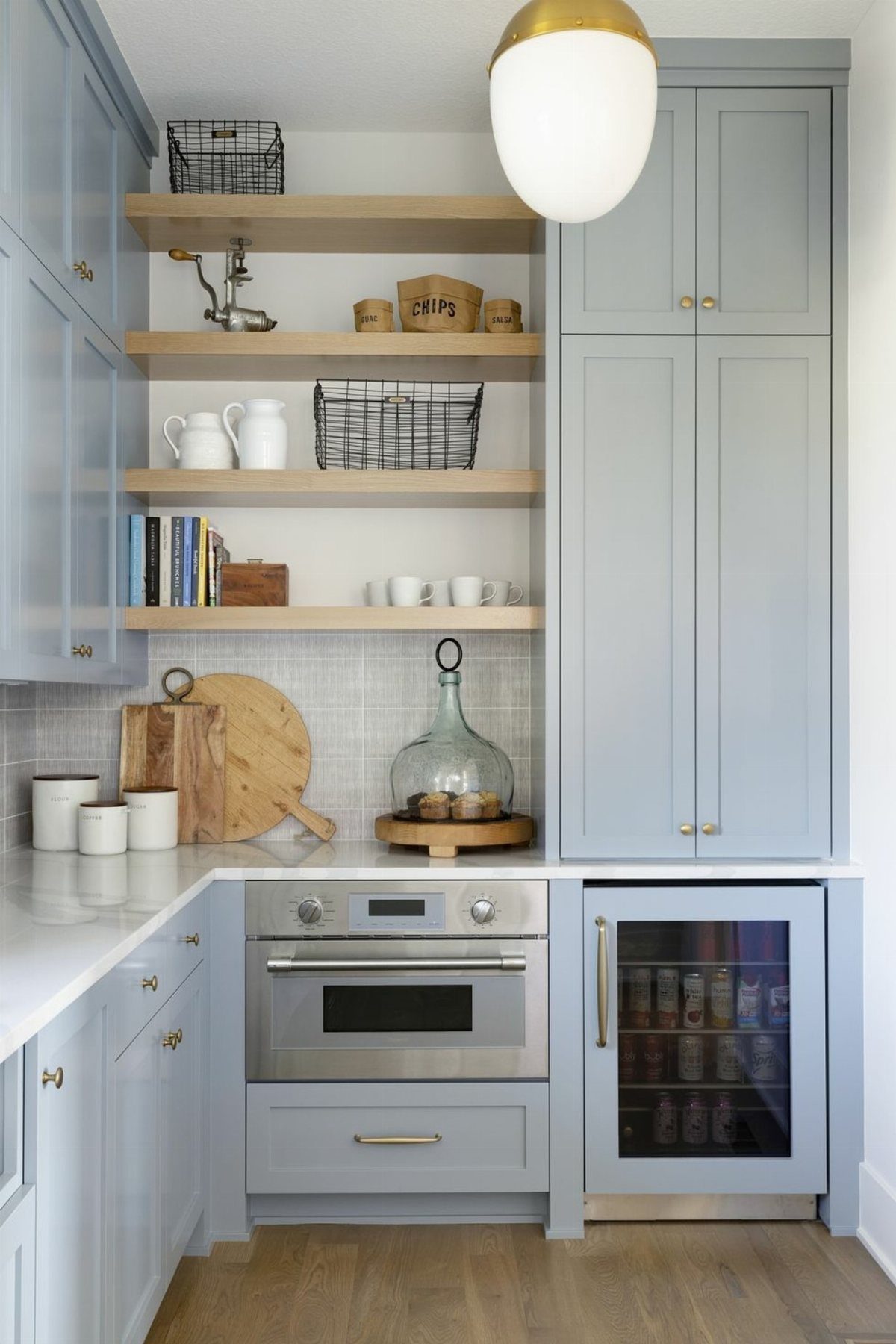 Light blue kitchen cabinets with open wood shelves and a built-in oven.