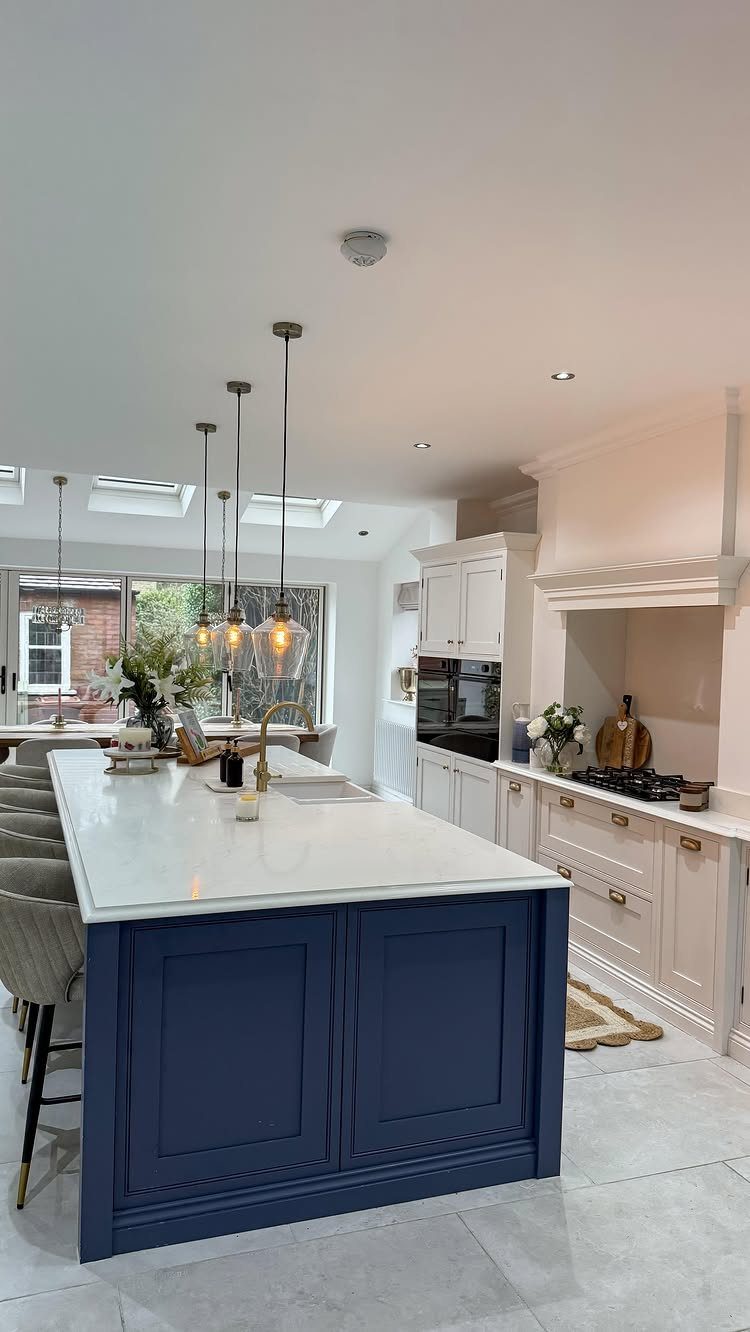 Dark blue kitchen island with white marble countertop in a bright modern kitchen