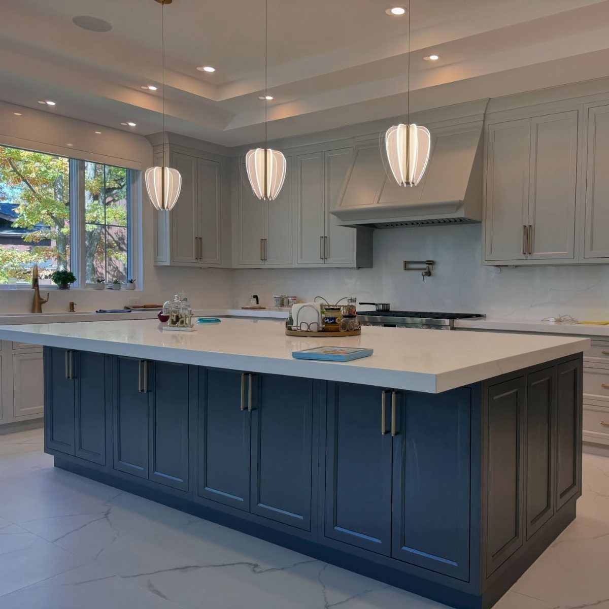 Dark blue kitchen island cabinets paired with light gray perimeter cabinetry and white countertops.