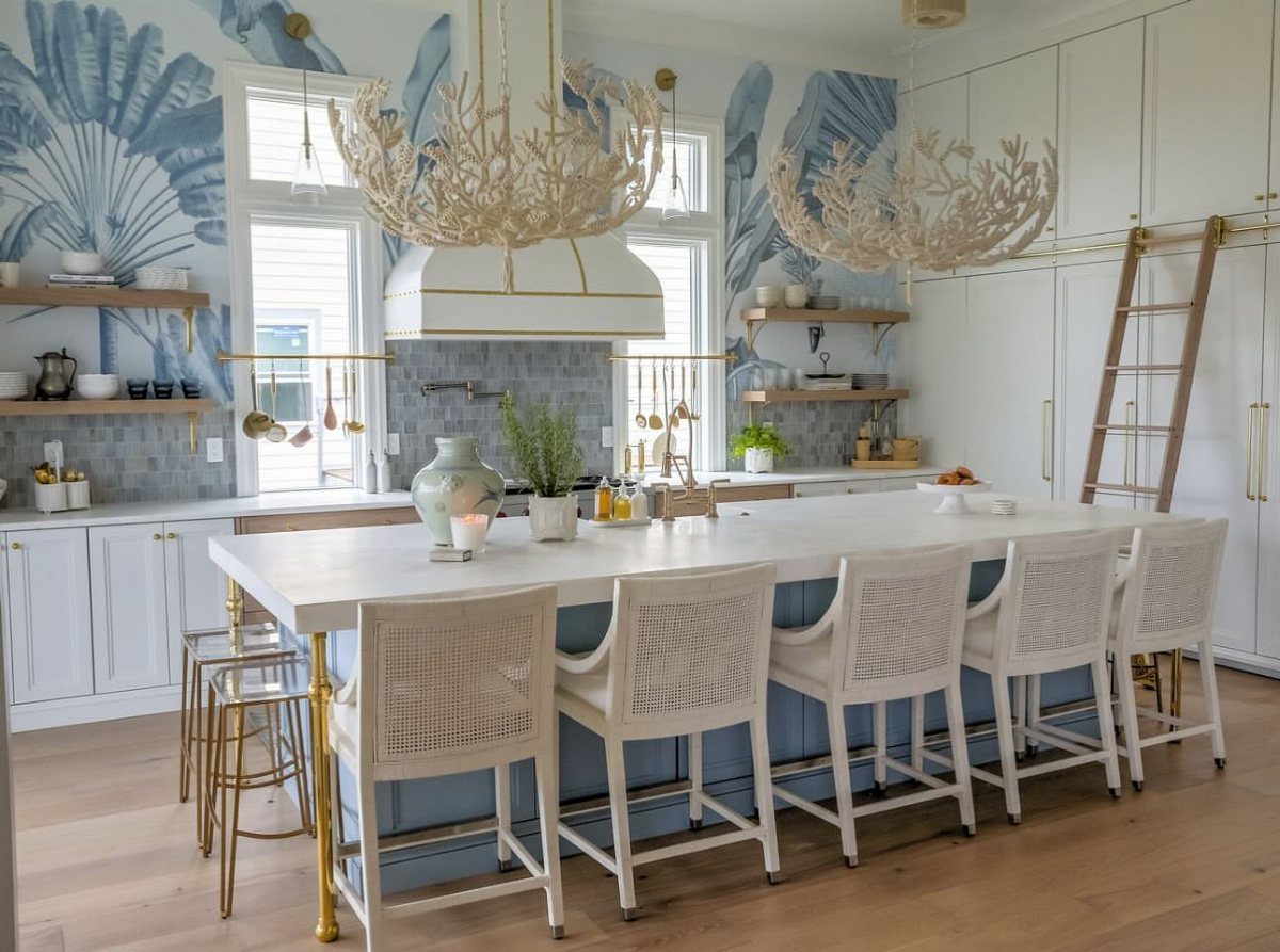 Light blue kitchen island with white countertops and coral-shaped chandeliers in coastal room