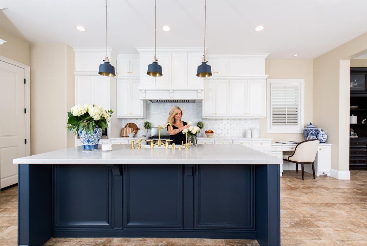 Navy blue kitchen island with white perimeter cabinets and white countertops in a bright room