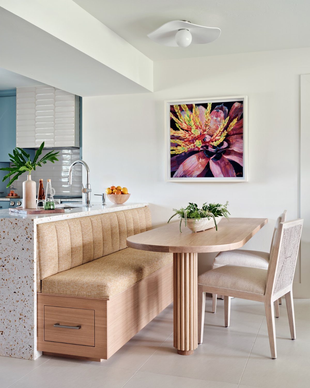 Breakfast nook with a tan banquette seat featuring built-in wooden storage drawers.