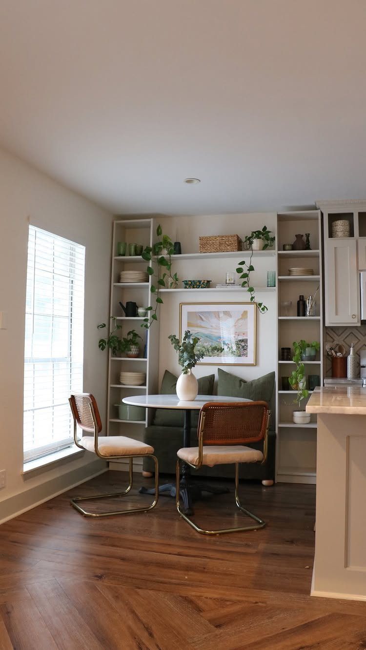 Breakfast nook with green banquette seating and white built-in storage shelving units.