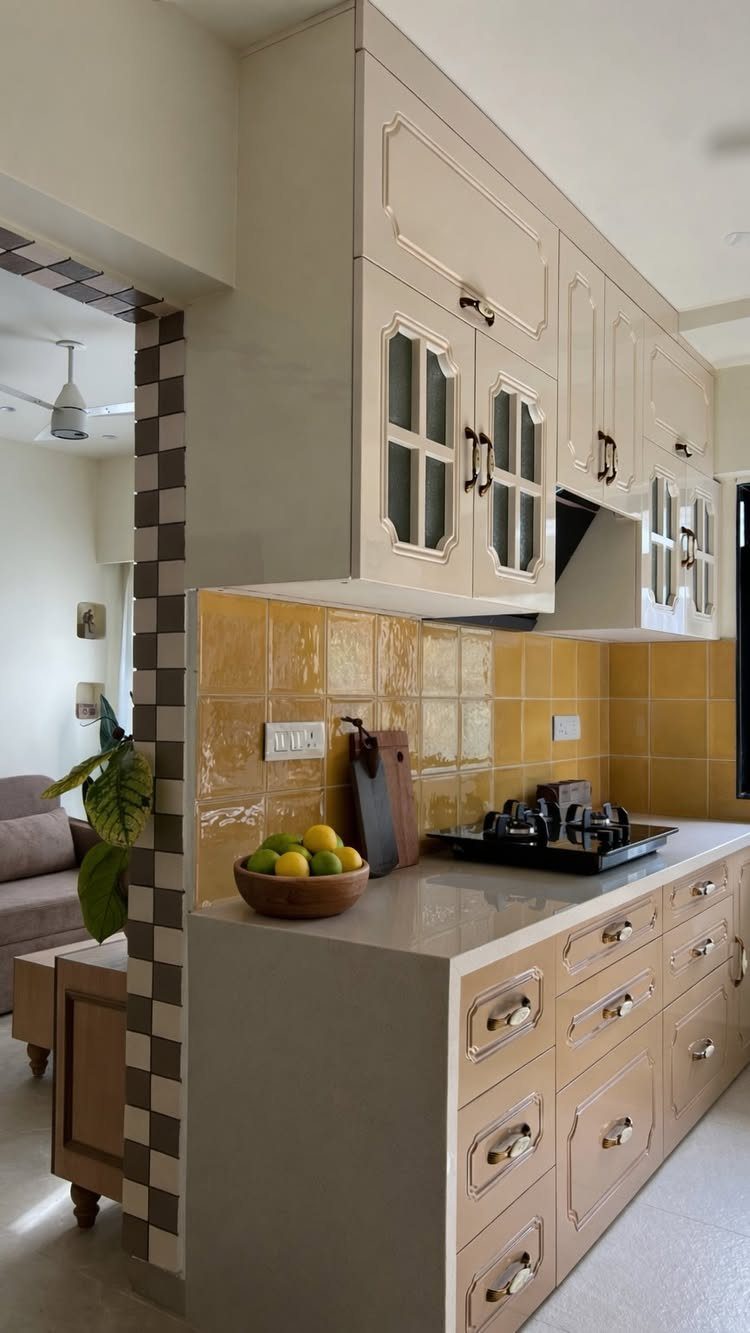 Cream and yellow kitchen cabinets with a glossy yellow tiled backsplash and gray countertop.