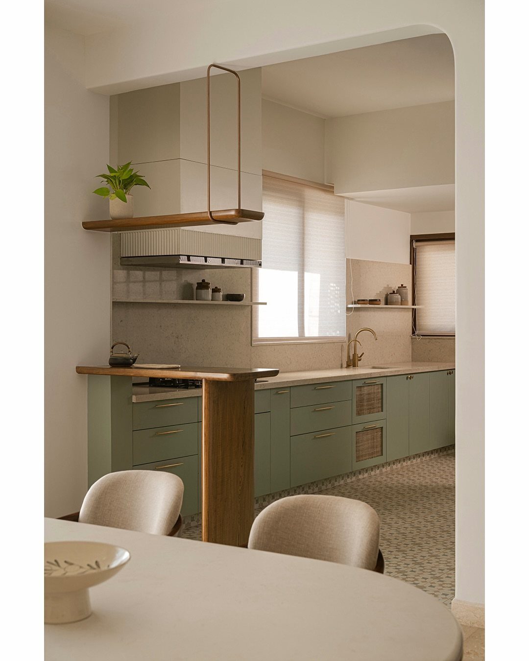 Sage green kitchen cabinets in an open layout with a wooden breakfast bar.
