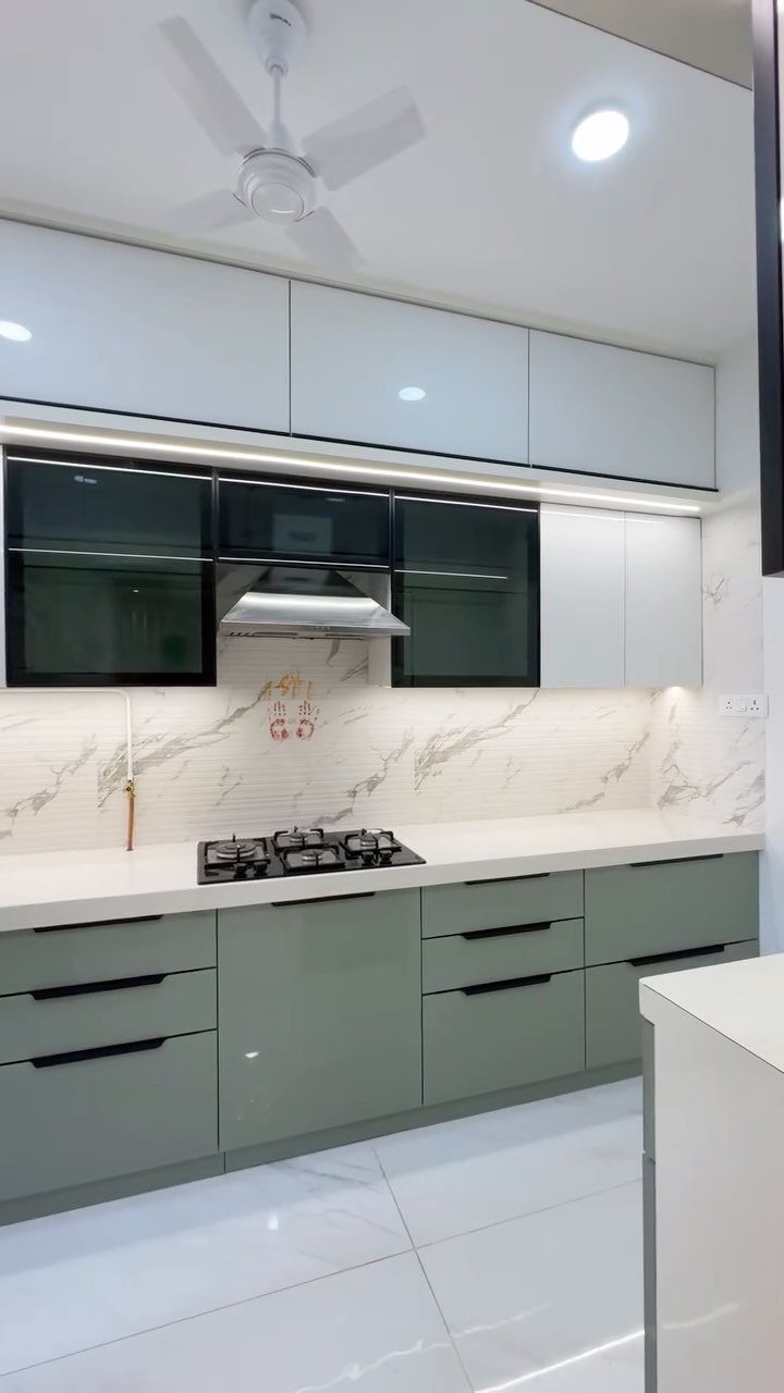 Olive green lower kitchen cabinets with white upper cabinets and marble countertops.