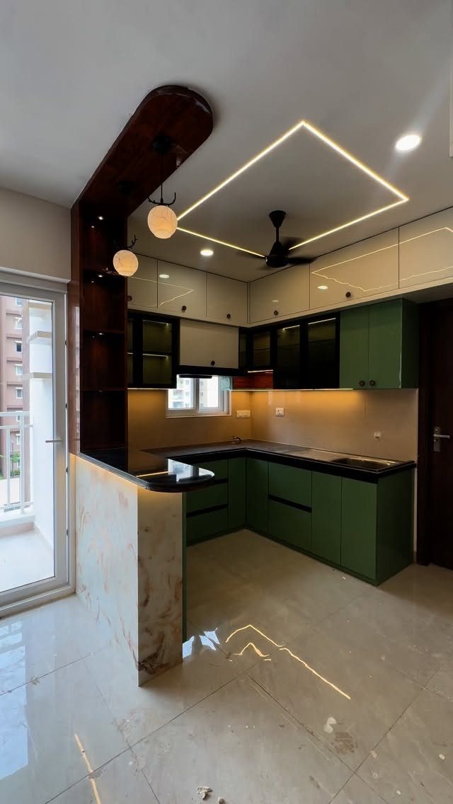 Green lower and white upper kitchen cabinets with black countertops and marble island.