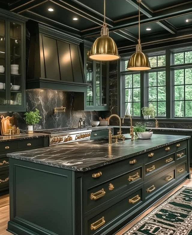 Emerald green kitchen cabinets with black marble countertops and gold hardware and lighting.