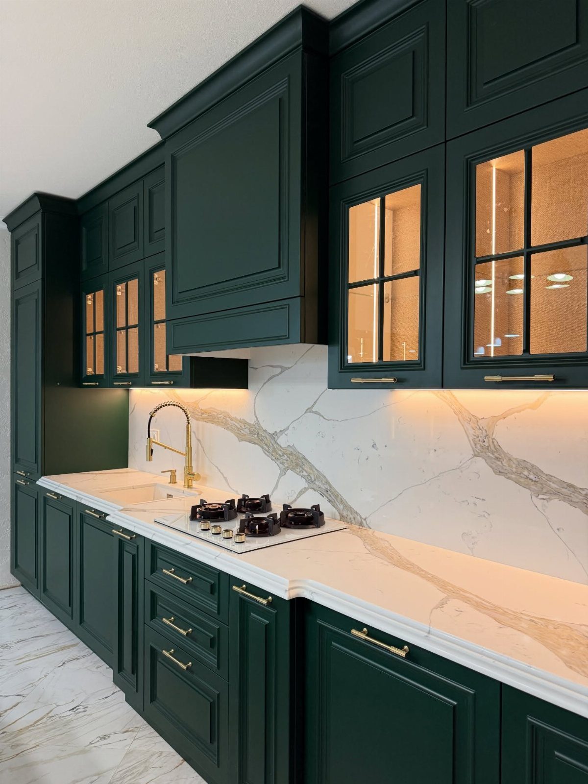 Emerald green kitchen cabinets paired with white marble countertops and gold hardware accents.