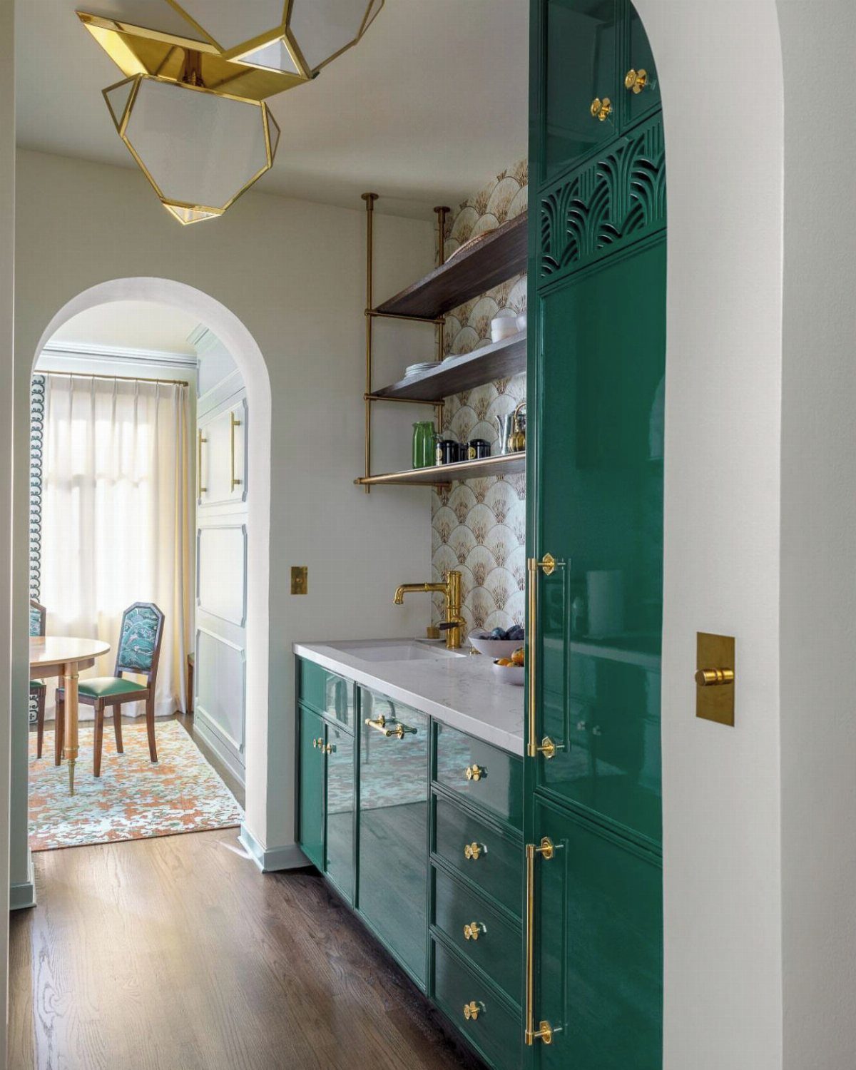 Glossy emerald green kitchen cabinets with gold handles and a white marble countertop.