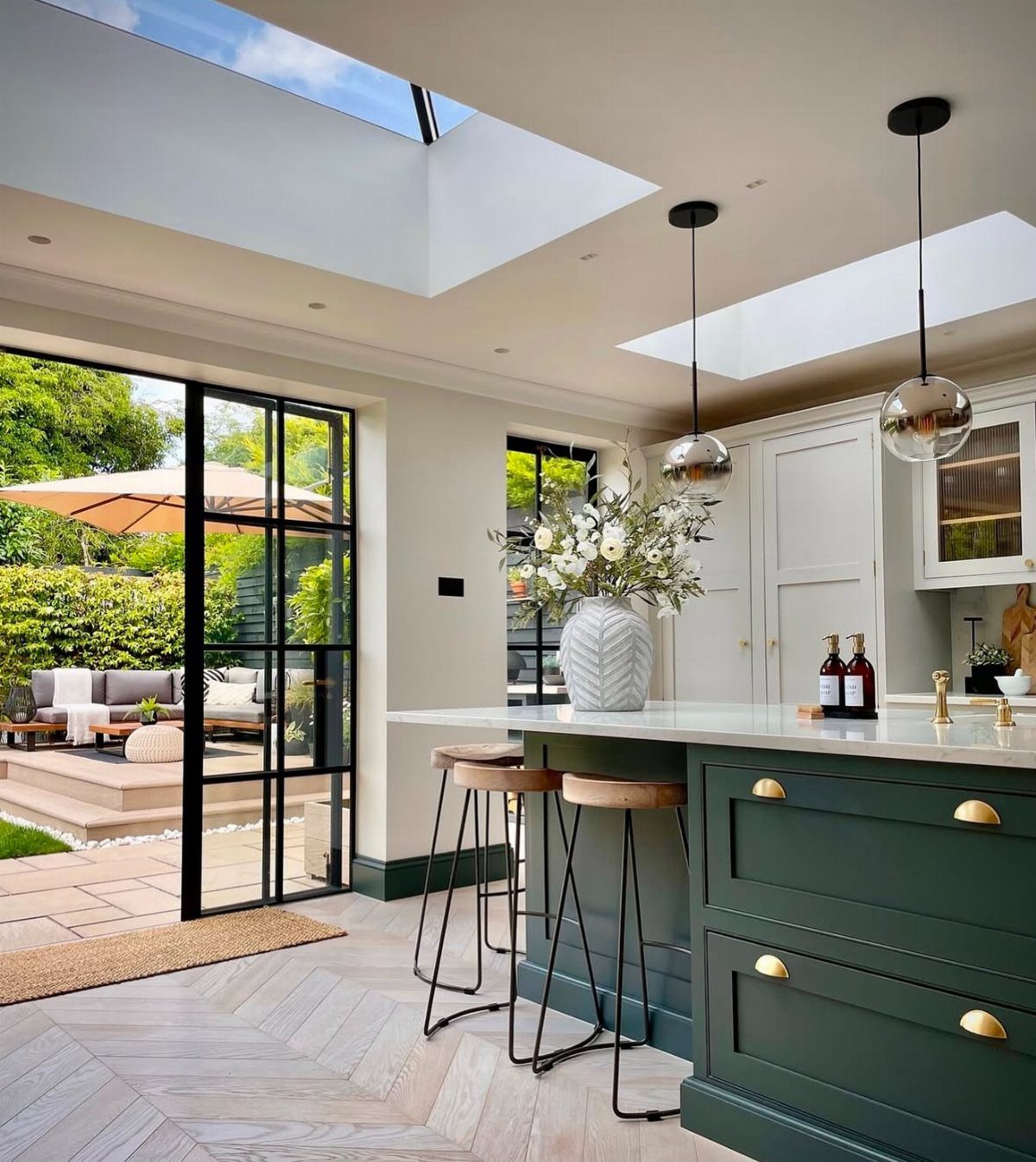 Emerald green kitchen cabinets in an open concept room with large glass doors.
