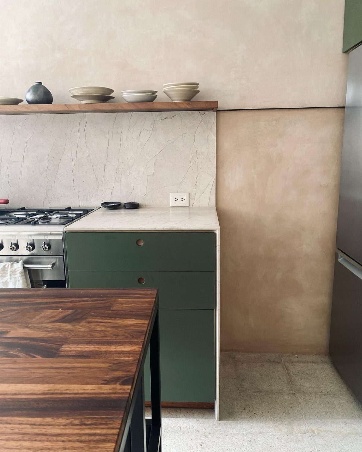 Avocado green kitchen cabinets with white countertops and a marble backsplash.
