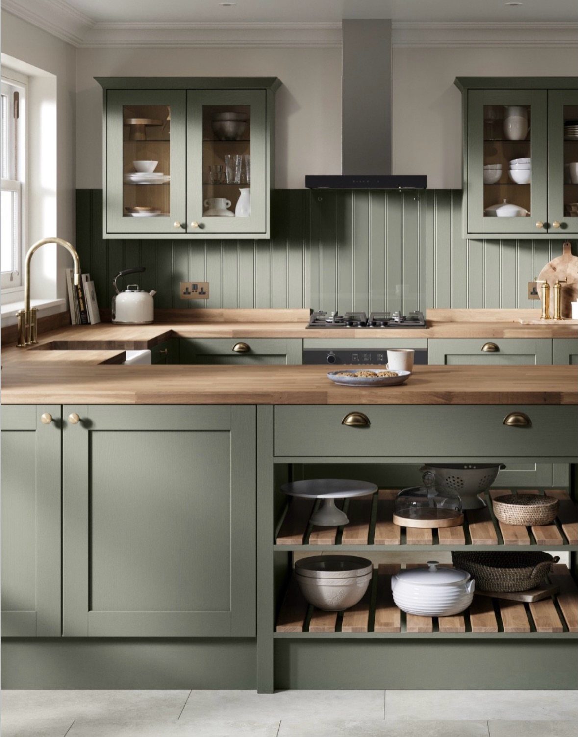Sage green kitchen cabinets with light wooden countertops and a matching beadboard backsplash.