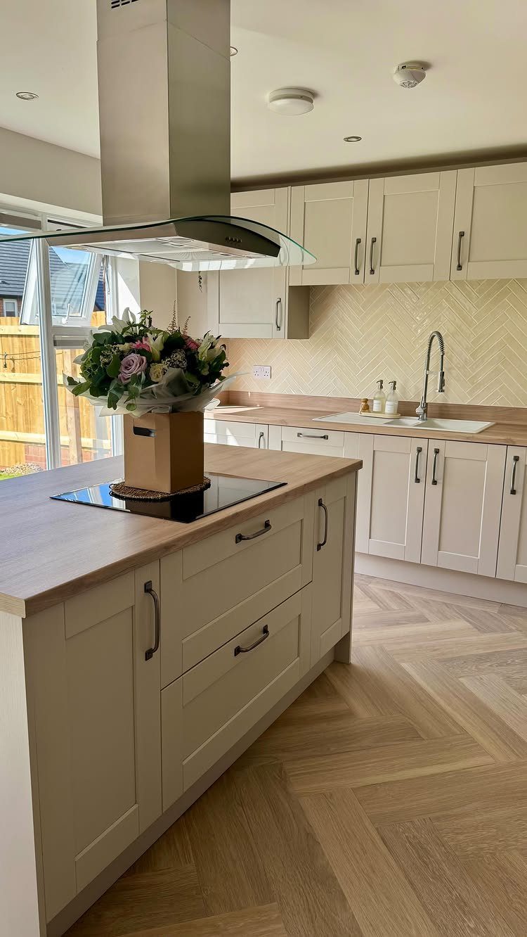 Herringbone patterned backsplash in a farmhouse kitchen with cream cabinets and wood countertops.