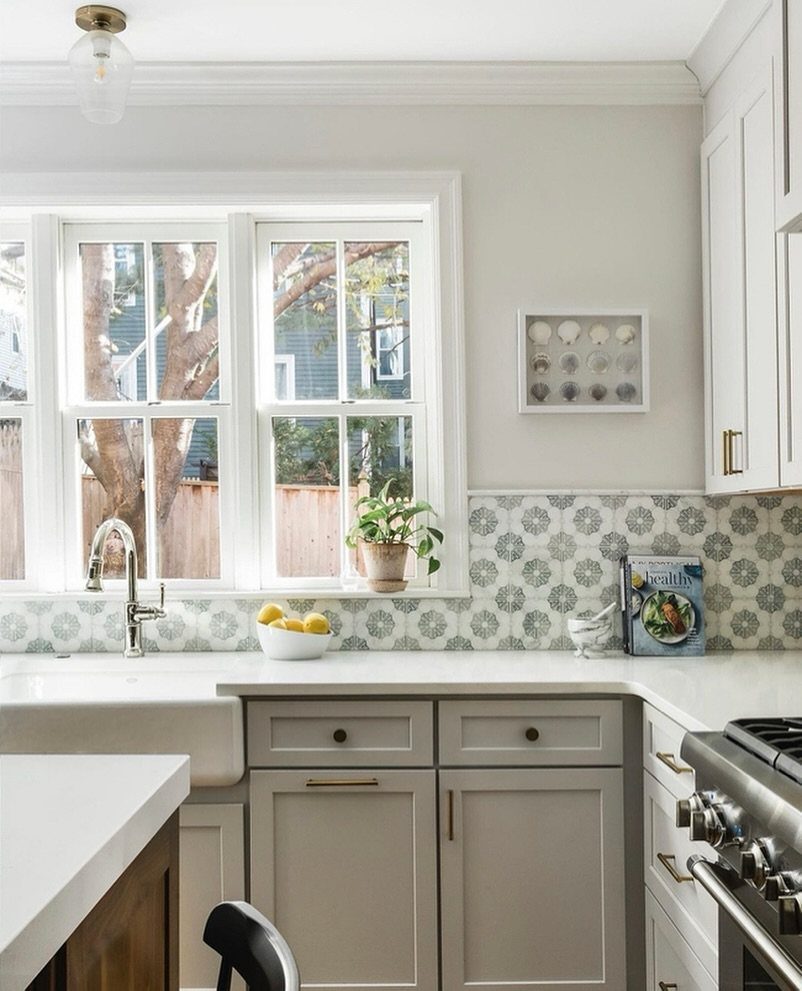 Patterned white and grey tiles as a kitchen backsplash with a farmhouse sink.