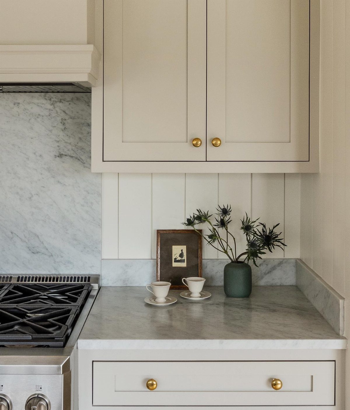 White vertical wood paneling backsplash with marble countertops and white kitchen cabinets.