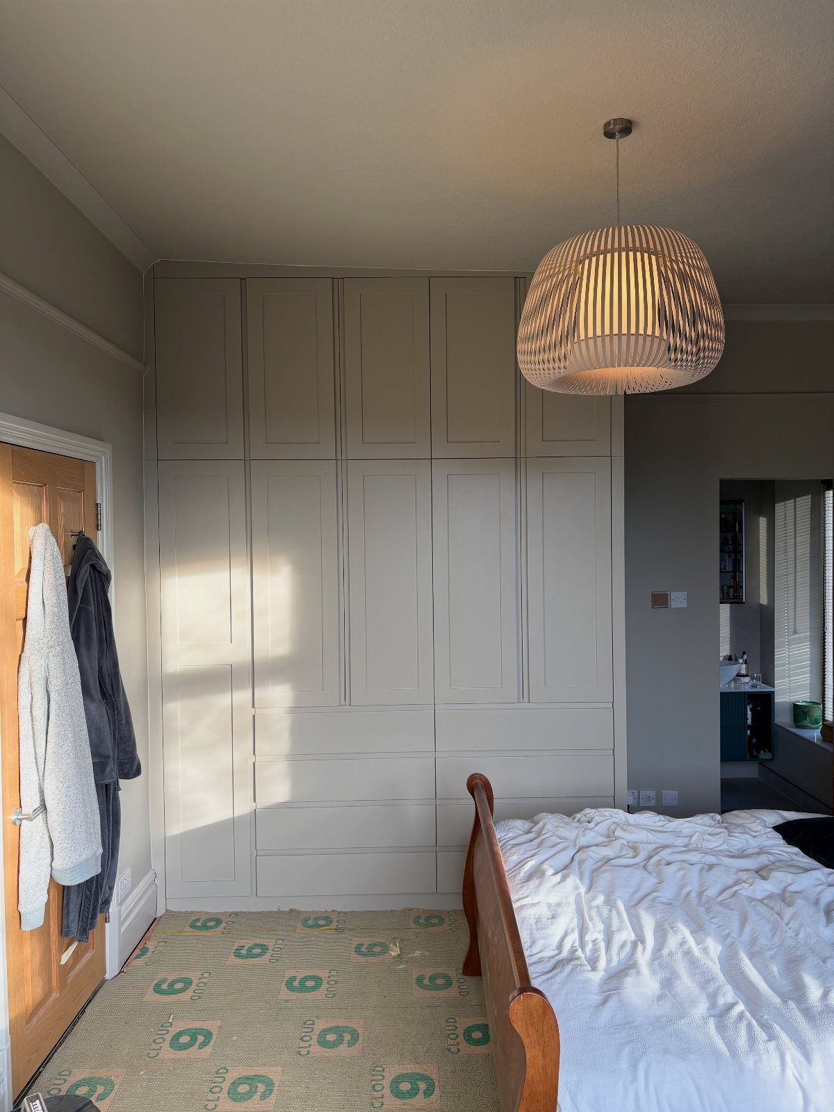 Floor to ceiling grey paneled cabinets in a bedroom with a wooden bed.