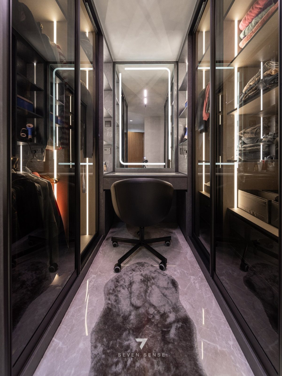 Black floor-to-ceiling glass-front cabinets with integrated lighting in a modern walk-in closet.
