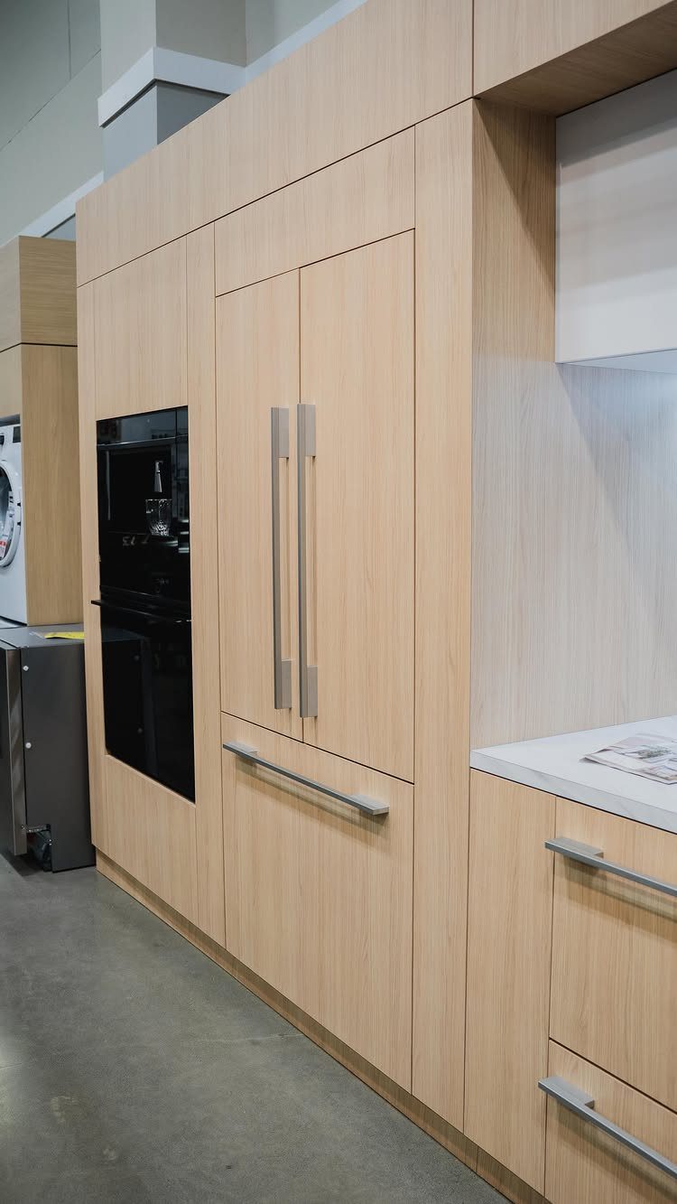 Light wood floor to ceiling cabinets with integrated oven and refrigerator in kitchen