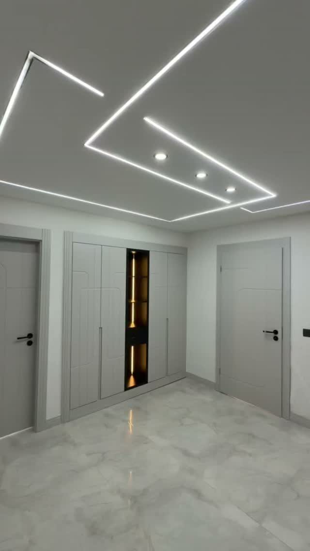 Grey floor-to-ceiling cabinets with integrated lighting in a modern room with marble floors.