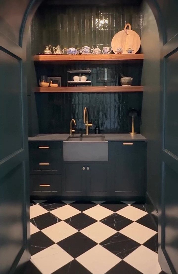 Dark green and black kitchen nook with gold accents and checkered flooring