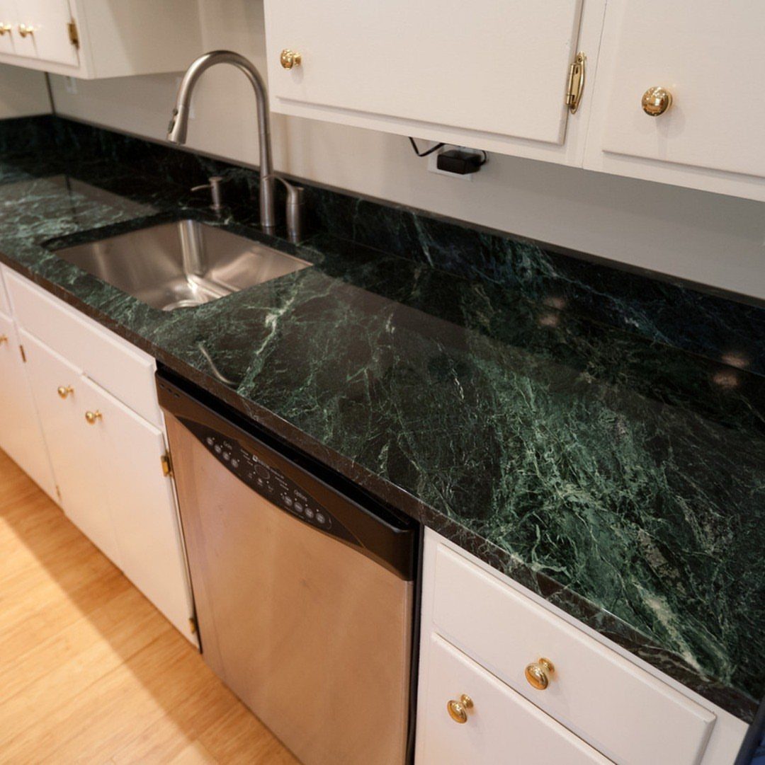 Dark green and black marbled granite kitchen countertop with white cabinets and sink