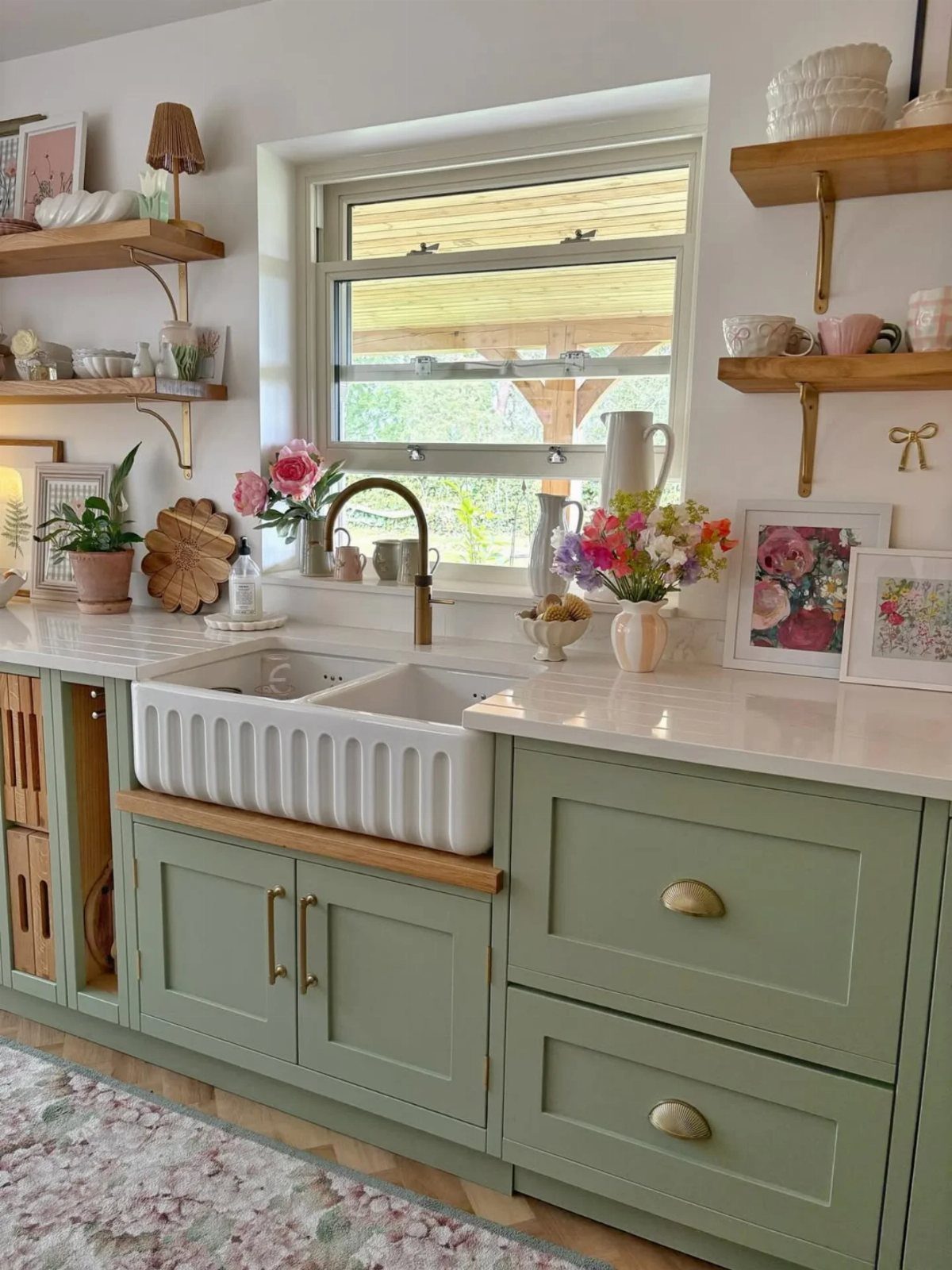 Garden green kitchen cabinets with gold fixtures and a white farmhouse sink.