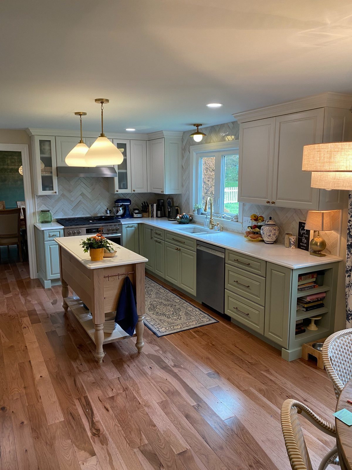 Light green lower cabinets and a wooden butcher block island in a kitchen.