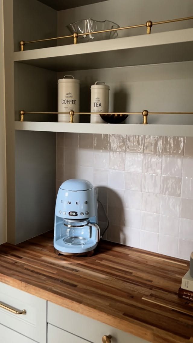 Light green kitchen cabinets with walnut butcher block countertop and blue espresso machine